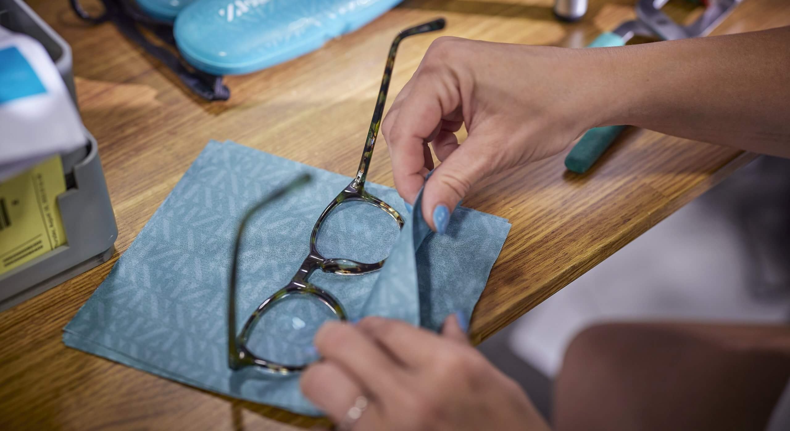 Glasses being cleaned with a blue microfiber cloth.
