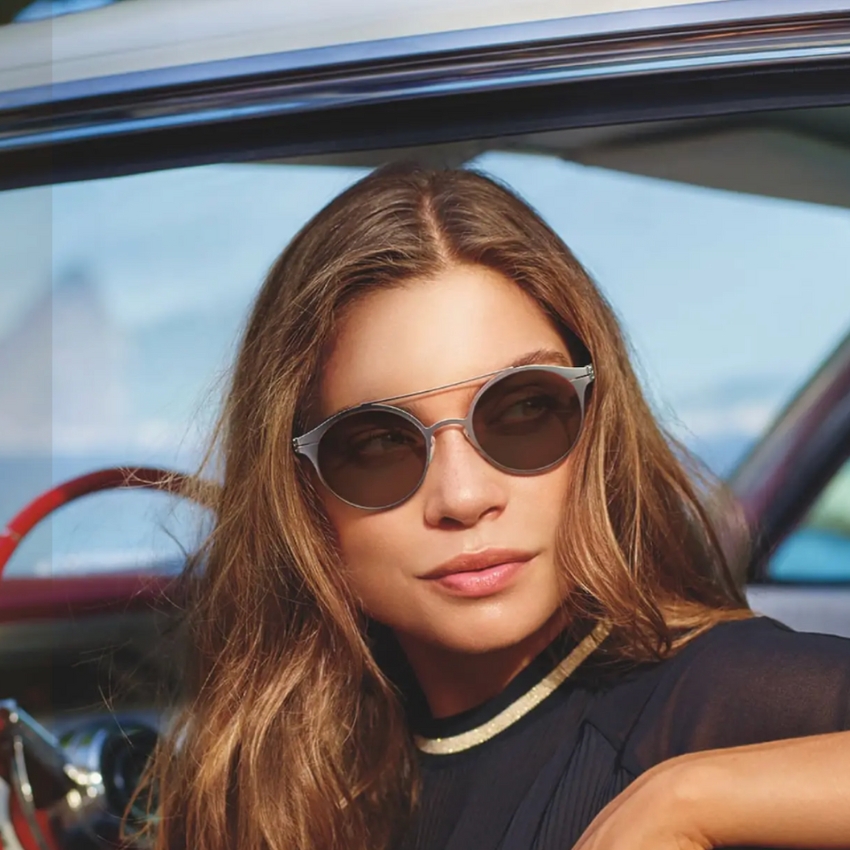 Woman wearing round, silver-framed sunglasses with dark lenses.