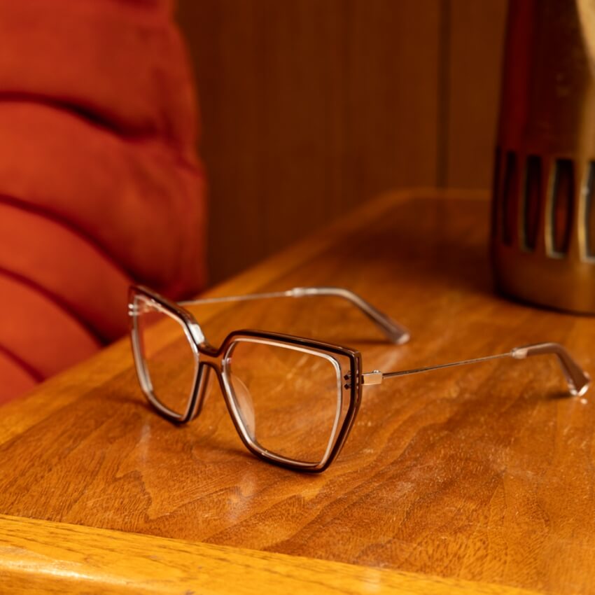 Retro-style oversized eyeglasses with light brown frames and thin metal temples on a wooden surface.