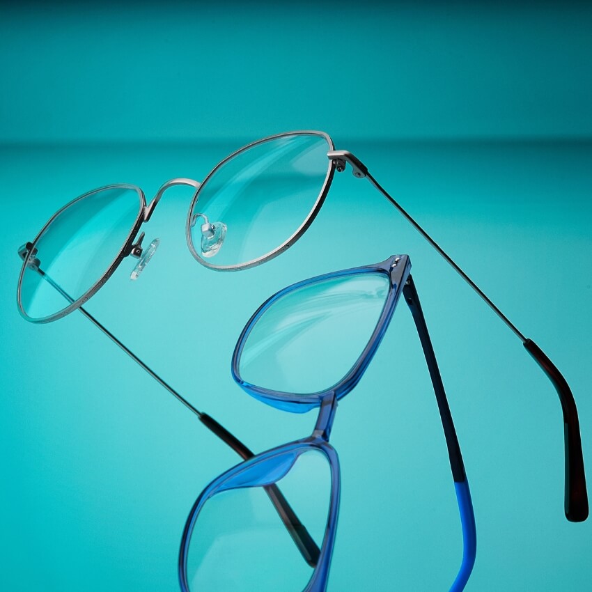 Two pairs of eyeglasses, one with silver round frames and one with blue rectangular frames.