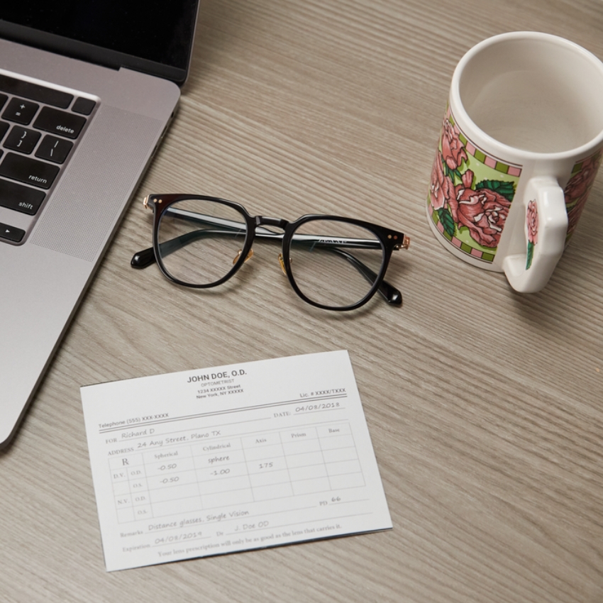 Black-rimmed eyeglasses near a prescription card from John Doe, O.D., dated 04/08/2018.