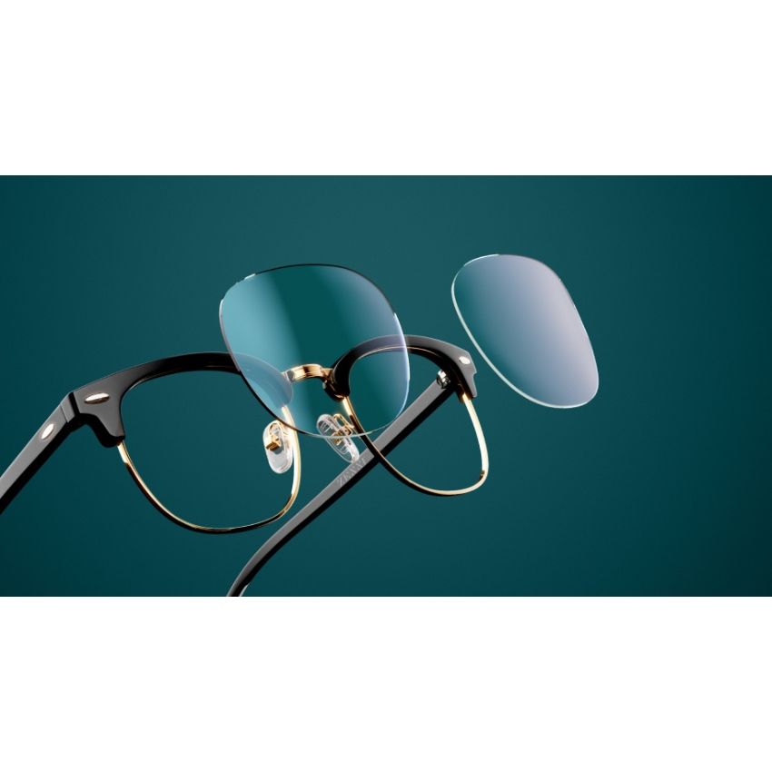 Black and gold eyeglasses with one lens removed and suspended in front of the frame.