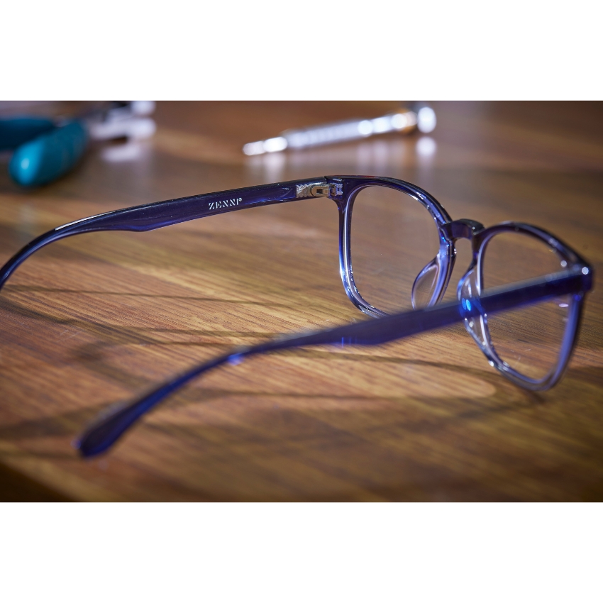 Blue eyeglass frames on a wooden surface with "ZENNI" inscribed on the temple.