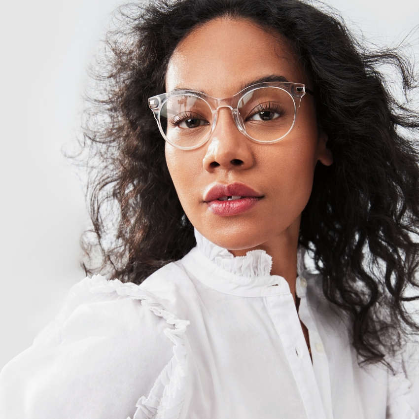Woman wearing clear-framed eyeglasses and a ruffled white blouse.